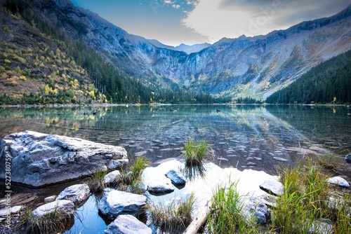 Avalanche lake shore in Glacier National Park with mountains reflected on the water surface photo