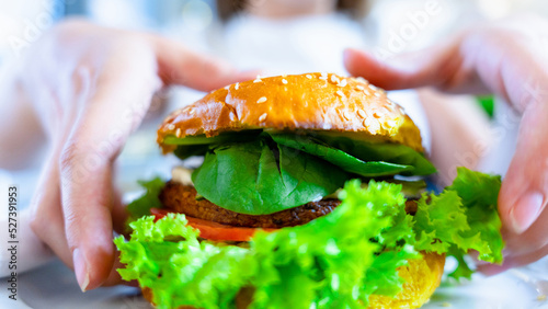 Hamburger vegan healthy vegetarian burger. Salad, avocado, vegetable on veggie sandwich eating cute woman. Tasty vegetarian healthy green food.