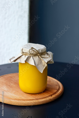 A  jar of honey on a wooden board on a black table, top view, space for text