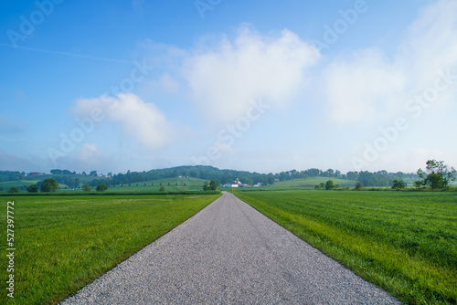 Straight country road through flat farm fields in Amish country  Ohio with rolling hills in the distance in summer