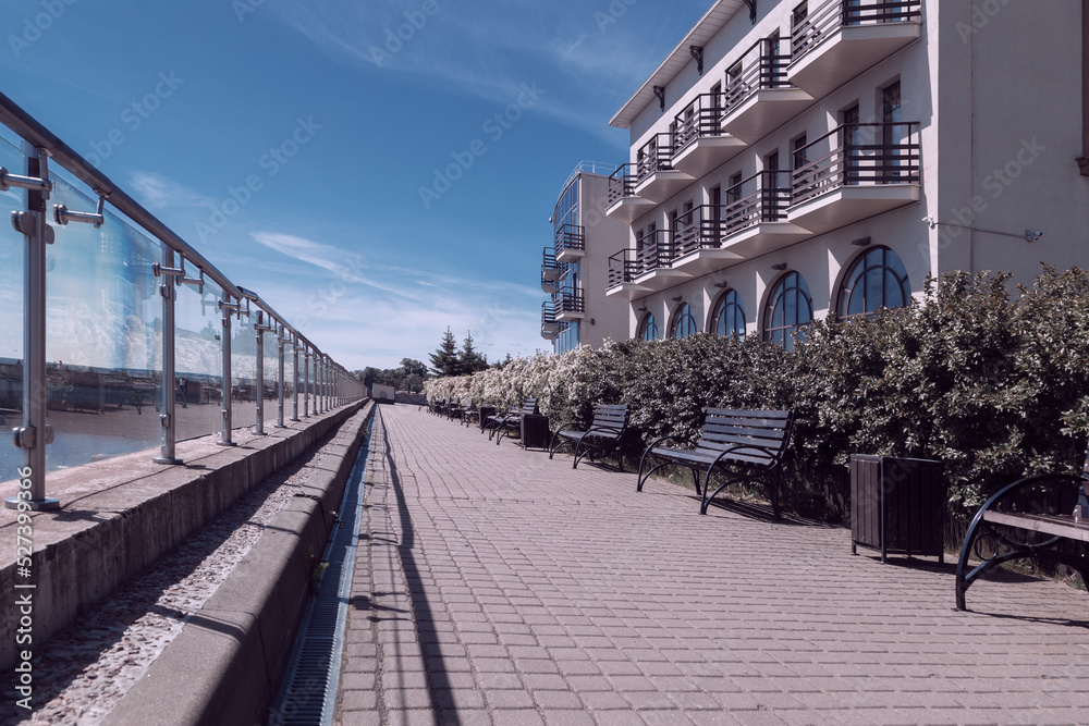 The embankment with beautiful white houses, greenery bushes and a glass fence.