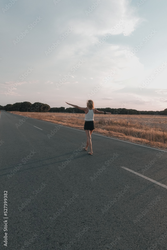 Obraz premium blonde-haired woman walking on the road at sunset in shorts