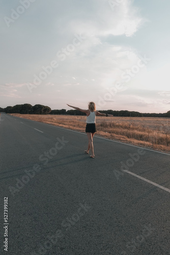 blonde-haired woman walking on the road at sunset in shorts