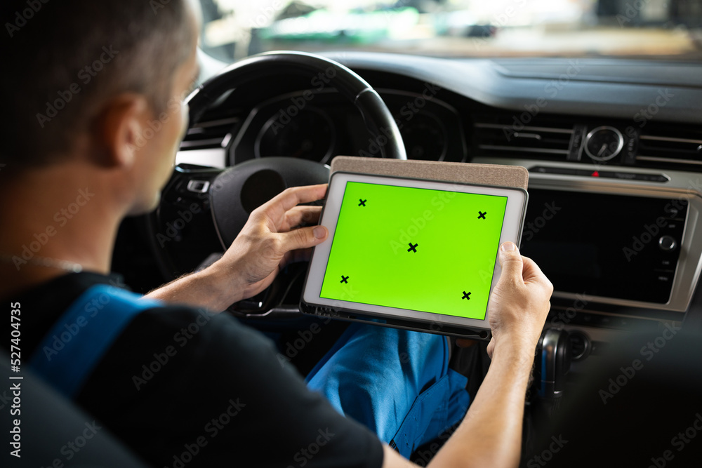 Unrecognizable vehicle service manager worker check and maintenance to repair the engine car in workshop. Mechanic running diagnostics software on tablet computer with green screen mockup chromakey