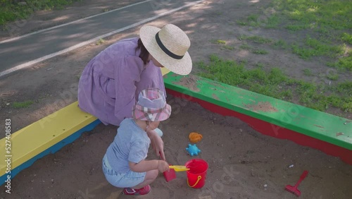 Mom and daughter play in the sandbox on the playground