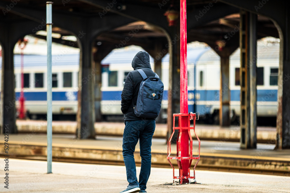 Fototapeta premium Tourist pulling luggage. Commuters walking at railroad station platform in Bucharest, Romania, 2022