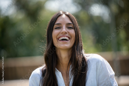 Beautiful young woman smiling while looking at camera standing in the park