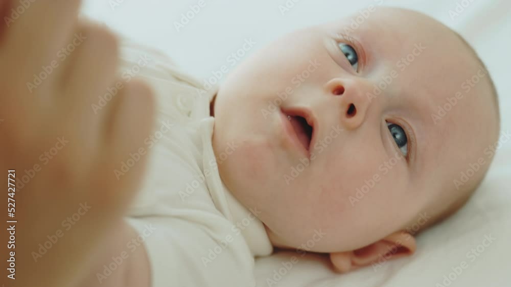 Top view of the newborn baby lying down and enjoying playing with mother. Portrait of the newborn baby lying down and playing with mom. Motherhood and newborn concept Top view of the newborn baby lying down and enjoying playing with mother. Portrait of the newborn baby lying down and playing with mom. Motherhood and newborn concept
