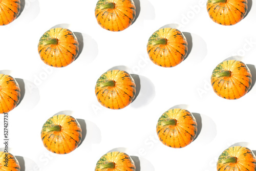 Flat lay pattern of bright orange pumpkins on white background. Top view