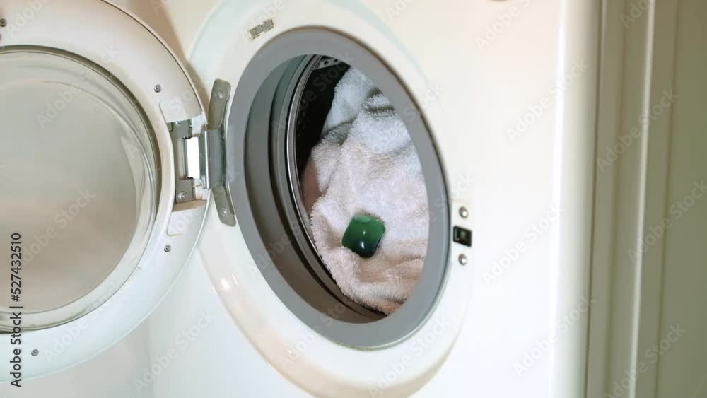 Laying the washing machine gel capsule in the open washing machine Laying the washing machine gel capsule in the open washing machine