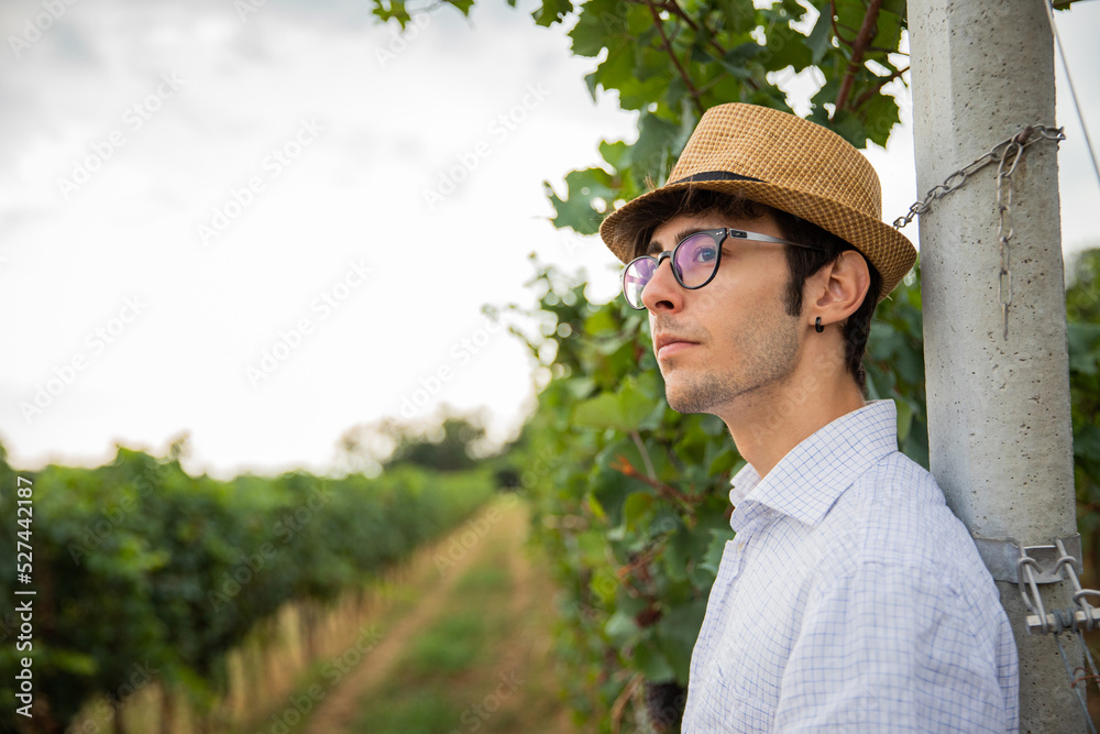 Portrait of a young farmer in his vineyard looking forward, confident gaze on the future.