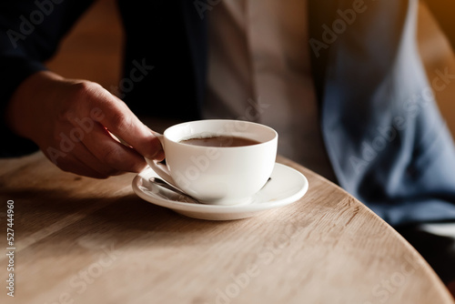 businessman in suit drinking coffee, wealthy successful man holding white cup of coffee or tea sitting by table in cafe, work break of businessman drinking hot drink.