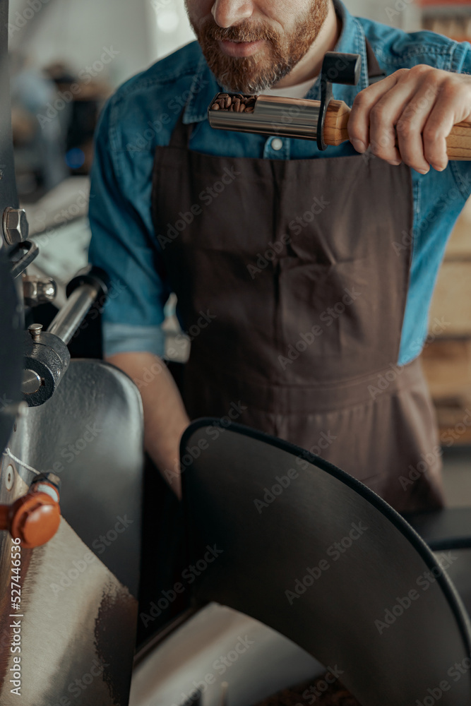 Obraz premium Close up of barista inhaling the aroma of coffee in own manufacturing of roasted coffee beans