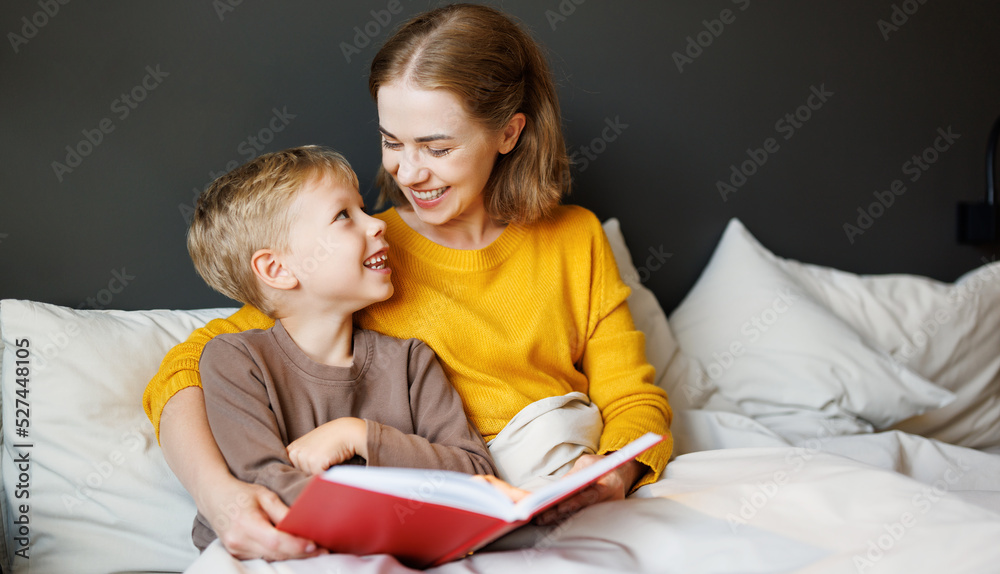 Happy mother and son reading book together on bed Happy mother and son reading book together on bed