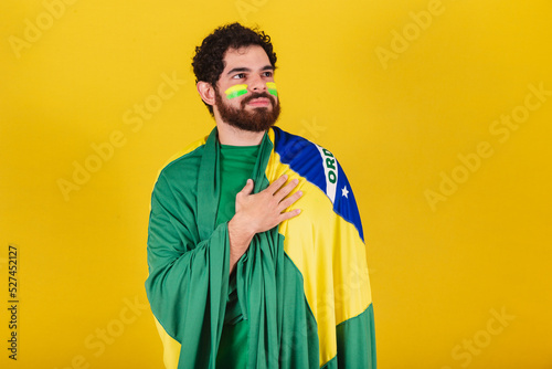 caucasian man with beard, brazilian, soccer fan from brazil, singing national anthem, with hand on chest.