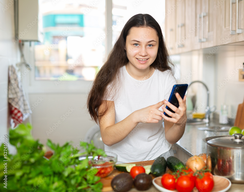 Housewife using her mobile phone during cooking at kitchen