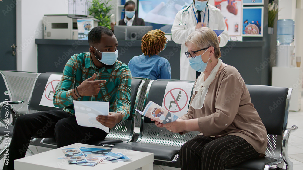 Obraz premium Multiethnic group of patients sitting in hospital reception to attend medical exam for covid 19 prevention. People with face mask having consultation appointment during coronavirus epidemic.