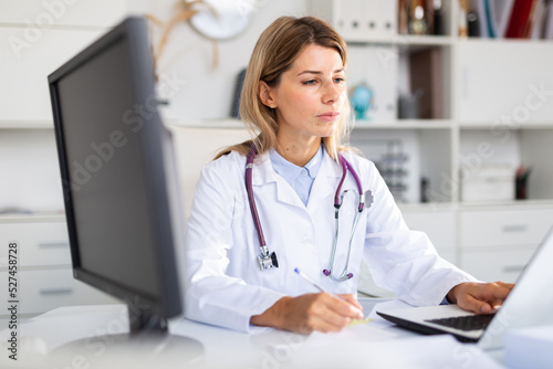positive female doctor with stethoscope working in cabinet