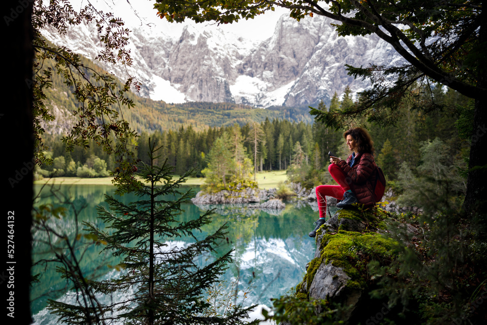 Woman Backpack Tourist Sitting Near An Alpine Lake Using Mobile Phone Woman Backpack Tourist Sitting Near An Alpine Lake Using Mobile Phone