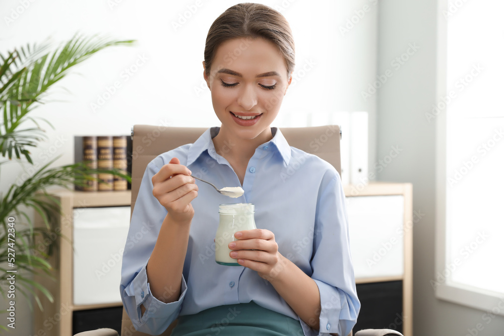 Young attractive woman with tasty yogurt in office Young attractive woman with tasty yogurt in office