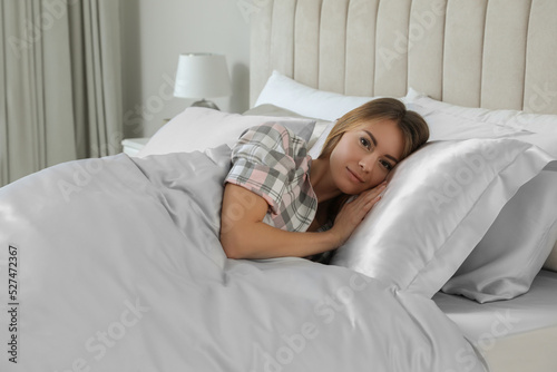 Beautiful woman lying in comfortable bed with silky linens