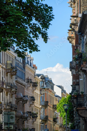 Fototapeta Naklejka Na Ścianę i Meble -  Perspective view over French street with tall haussmannian buildings blue sky with cumulus cloud