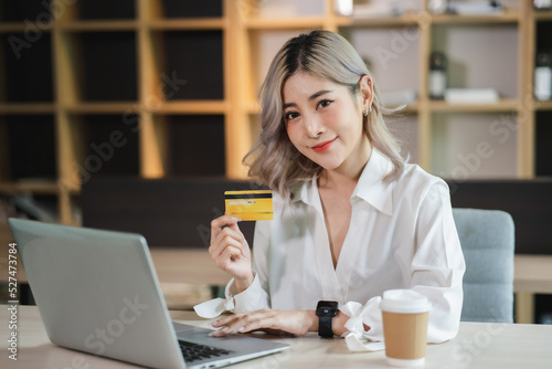 Young beautiful Asian woman smiling and happy, showing presenting credit card online shopping Online shopping, e-commerce, internet banking.