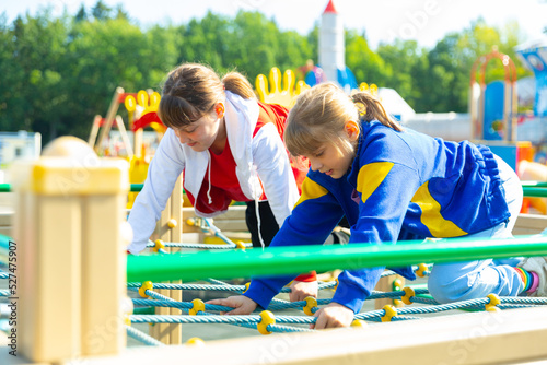 Two active teenage girls are walking on the playground in the yard on a summer day