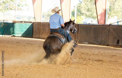 Cowboy riding reining horse slide stop