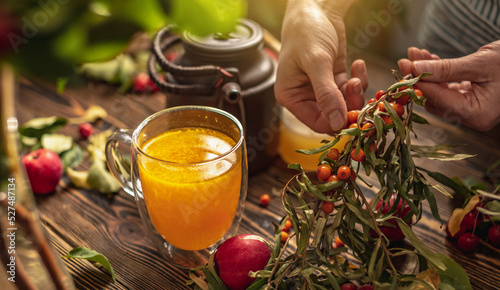 Foto Woman is making a tasty and healthy vitamin tea from fresh sea buckthorn berries