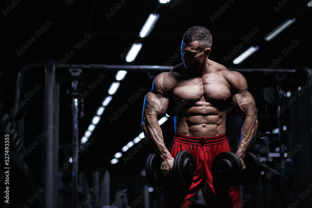 Muscular man bodybuilder training in gym and posing. Fit muscle guy workout with weights and barbell - obrazy, fototapety, plakaty 