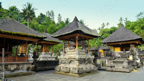 mehrere hinduistische Tempel in Tirta Empul in Bali umgeben von grünen Bäumen unter blauem Himmel