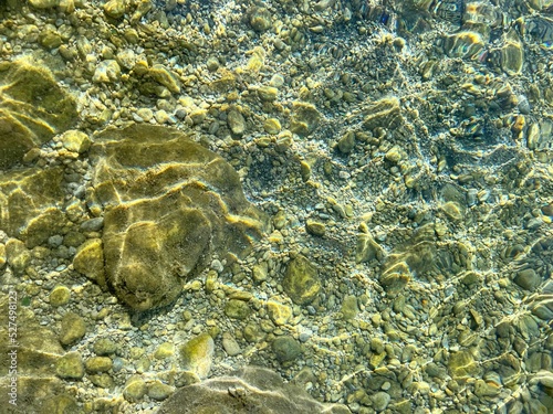 Sea transparent water with smooth stones  pebbles and sand at the bottom of the sea.
