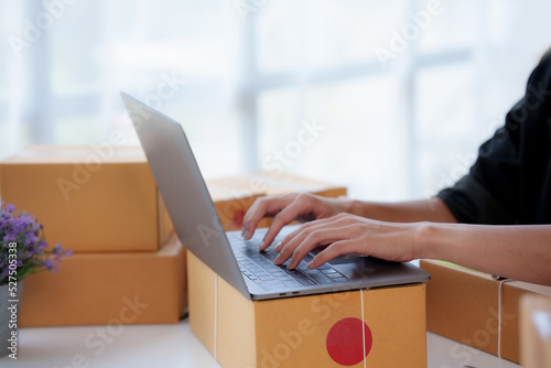 Close-up of a young woman who owns an online packaging business for a customer. Check the customer address list to properly pack and ship to the customer. © amnaj