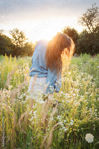 Beautiful girl  walking on field on summer with wildflowers.