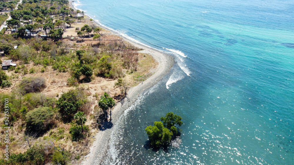 People returning from the market walking along the stunning rugged coastline of tropical Atauro Island, Timor Leste, aerial drone view from above