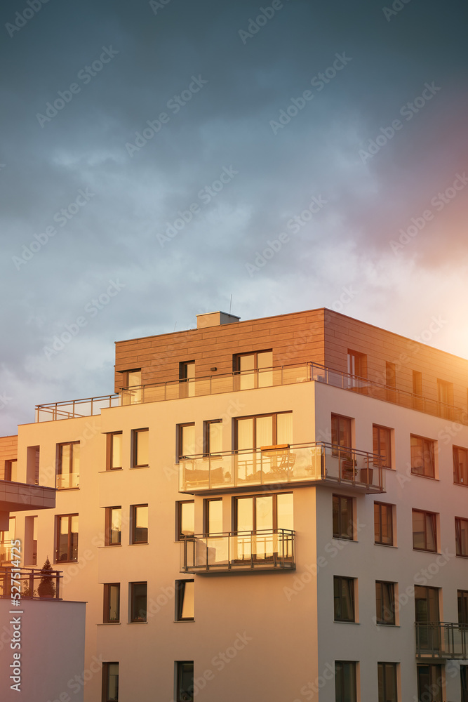 The apartment building at sunset. Condominium construction in the evening. Strong sunlight falls on the low-rise modern residential building The apartment building at sunset. Condominium construction in the evening. Strong sunlight falls on the low-rise modern residential building