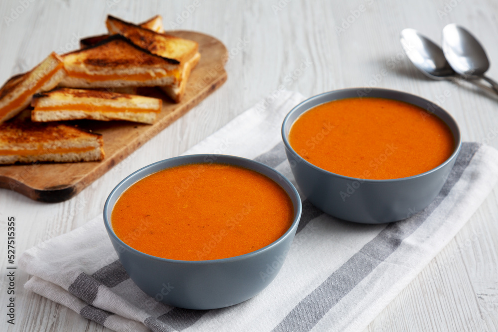 Homemade Tomato Soup with Grilled Cheese on a white wooden background, low angle view.