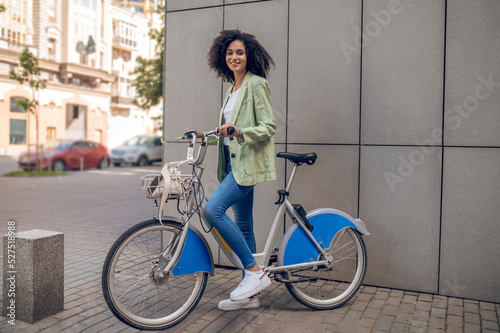 Curly-haired girl in trendy clothes with a bike