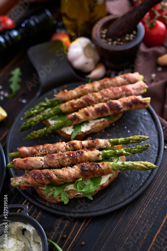 Tasty breakfast - toasts with cream cheese and Asparagus wrapped with bacon and spices on a plate