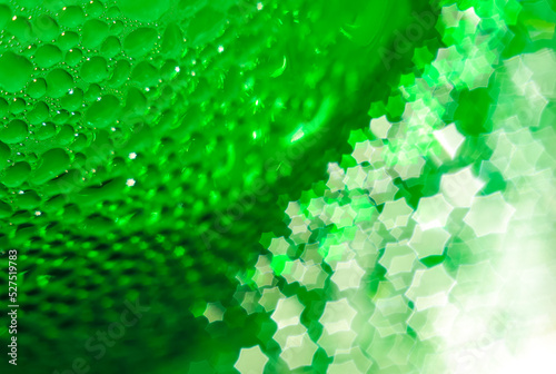 Green glass bottle, selective focus, beautiful blurred bokeh. Close-up. Drops of water on the glass passing in the bokeh in the form of a hexagonal star.