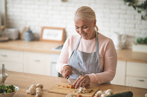 Foto A blonde woman in apron in the kitchen looking busy