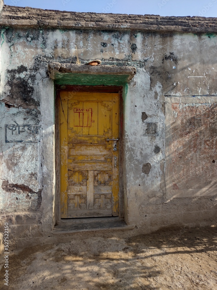 Indian old village house closed yellow door grunge wall Indian old village house closed yellow door grunge wall
