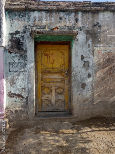 Indian old village house closed yellow door grunge wall © Dipak
