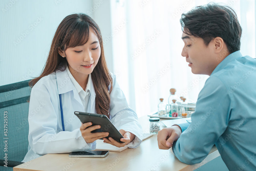 Female doctor and young male patient while consult and .explain. Doctor and patient sitting together at table in examination room. Female doctor and young male patient while consult and .explain. Doctor and patient sitting together at table in examination room.