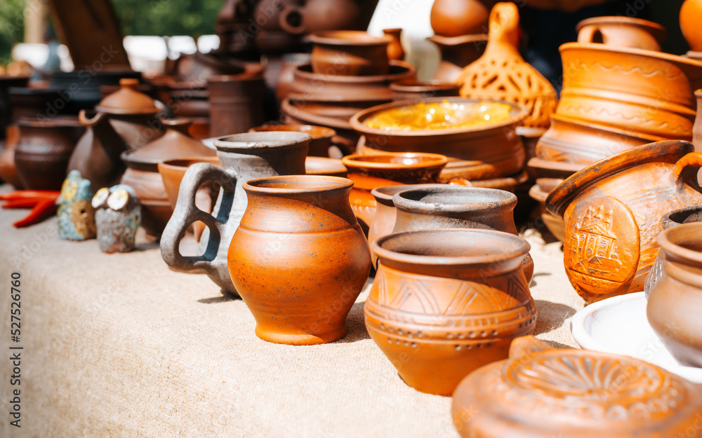 Side view of craft clay pottery, handmade ceramic mugs pots in medieval  rustic style outdoors on a sunny day. Sale of kitchen utensils. Close-up,  selective focus Stock Photo