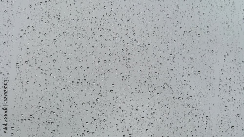 Wet glass. Drops of water on glass. Abstract background. Grey sky. Overcast weather. Water flows. Close-up. Wet glass. Drops of water on glass. Abstract background. Grey sky. Overcast weather. Water flows. Close-up.