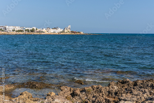 Scenic view of Torre San Giovanni and its rocky shore, with lighthouse in the background, marina di Ugento, Salento, Puglia, Italy photo
