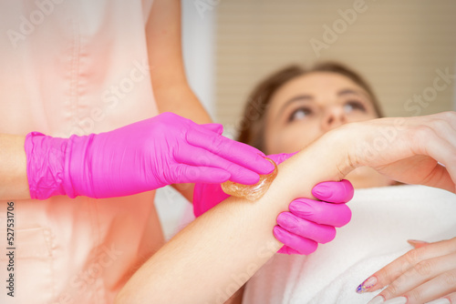 Waxing. Depilation hand and arm of the young woman lying in the spa salon