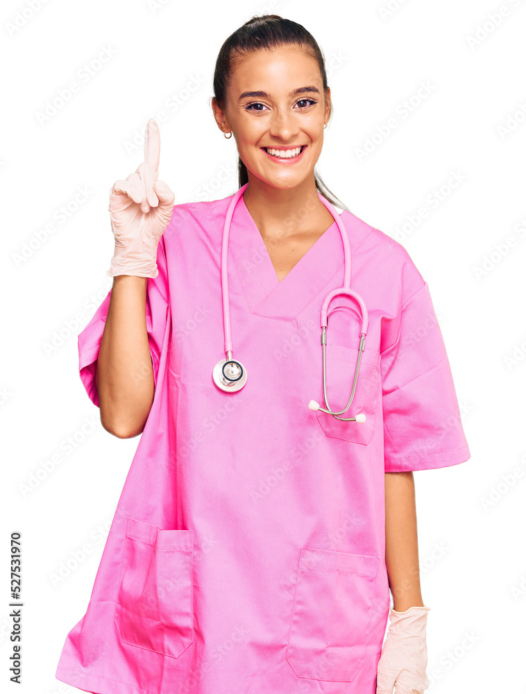 Young hispanic woman wearing doctor uniform and stethoscope pointing finger up with successful idea. exited and happy. number one. Young hispanic woman wearing doctor uniform and stethoscope pointing finger up with successful idea. exited and happy. number one.